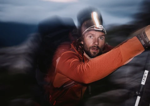 Outdoor Imagebild - Person mit Stirnlampe und Wanderstöcken im Gebirge