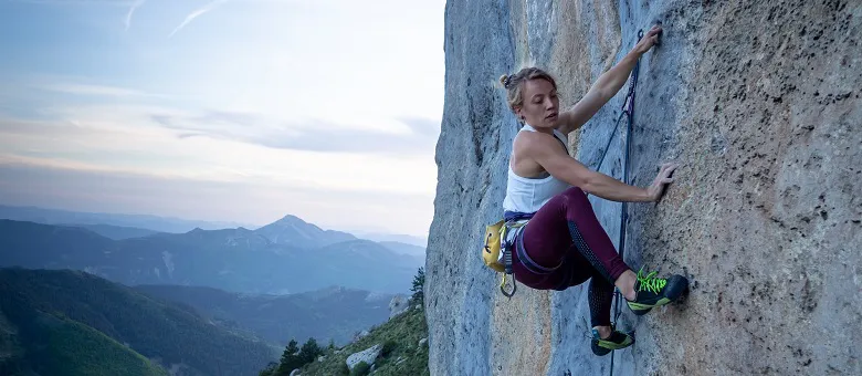 Kletterschuhe im Einsatz - Person klettert im Freien im Gebirge an einer vertikalen Felswand