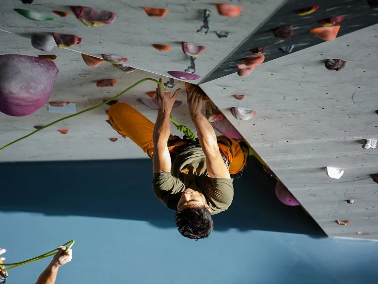 Outdoor Imagebild - Person klettert in der Halle an einer steilen Kletterwand mit Griffen.