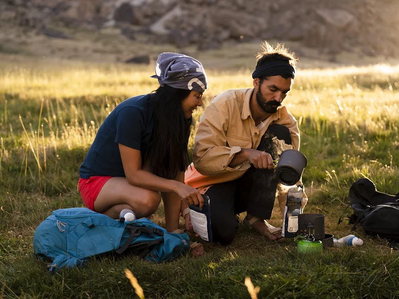 Outdoor Imagebild - Zwei Personen bereiten draußen eine Mahlzeit zu mit einem Outdoorkocher