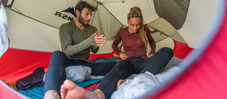 Outdoor-Imagebild - zwei Personen mit langer Funktionsunterwäsche bekleidet sitzen in einem Zelt.