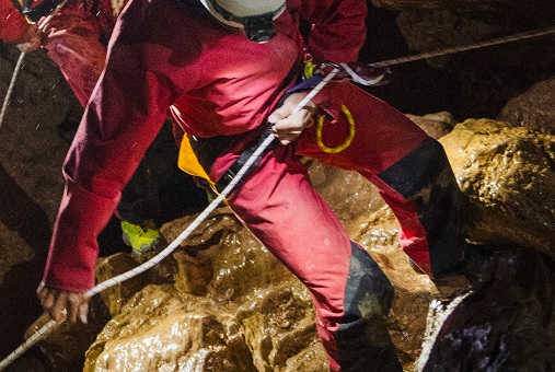 Person klettert am Fels in einer Tropfsteinhöhle