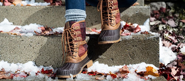 Kamik Stiefel auf einer Steintreppe umgeben von Laubblättern und Schnee