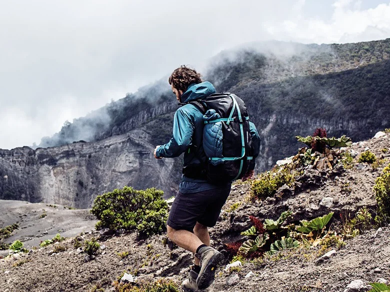 ORTLIEB Atrack Rucksack Outdoor Imagebild - Person im Gebirge mit einem blau schwarzen Rucksack bewegt sich schnell fort.