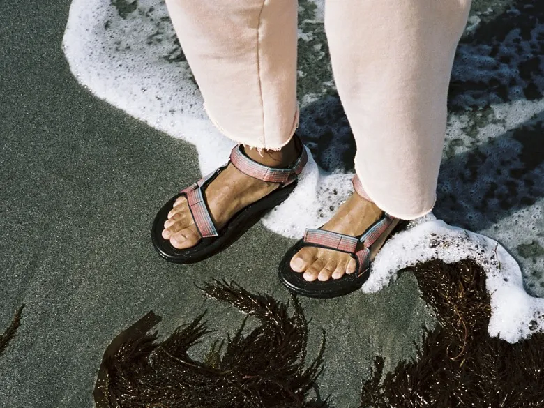 Outdoorsandalen im Einsatz - Person in Sandalen steht an Küste
