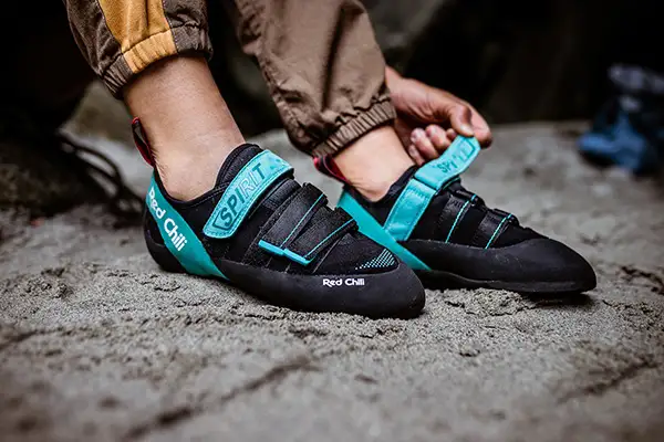 Kletterschuhe in Aktion - Person betätigt Klettverschluss an Red Chili Kletterschuhen