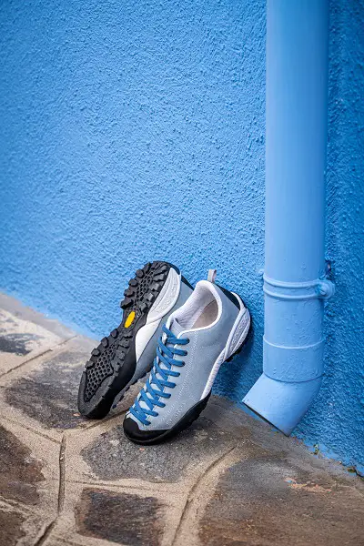 Scarpa Mojito Schuhe in Aktion - zwei blaue Scarpa Mojito Schuhe lehnen an einer blauen Wand mit einer blauen Dachrinne