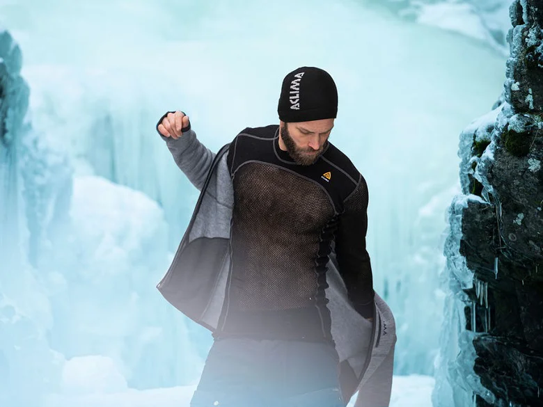 Outdoor Imagebild - Person steht vor einer eisigen Landschaft und zieht sich eine Jacke an