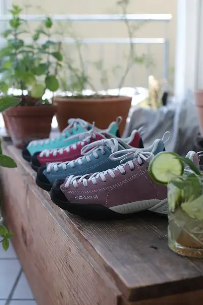 Vier Scarpa Mojito Schuhe stehen auf einem Tisch, auf welchen auch ein Mojito Getränk steht. Wortwitz und Eleganz werden vereint.
