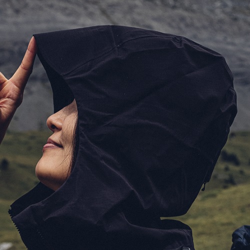 Person mit Hardshelljacke und Kapuze von der Seite